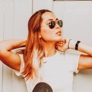 Headshot of a woman in sunglasses and white t-shirt.