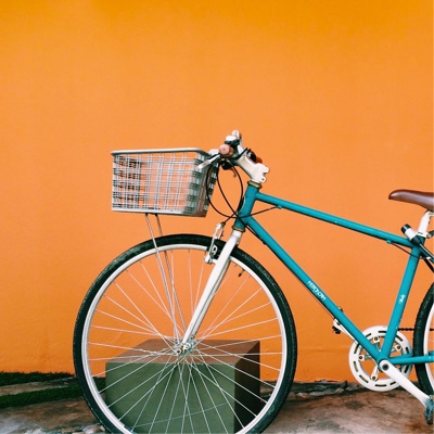 Photo of a turquoise bike against an orange wall.